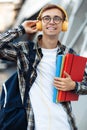 Close-up portrait of young male student in casual outfit with yellow headphones holding folders while listening music on the Royalty Free Stock Photo