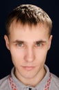 Close-up portrait of a young man, red embroidery on the polo collar, on a black background Royalty Free Stock Photo