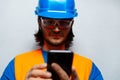 Close-up portrait of young man, construction worker engineer, looking in smartphone, wearing safety equipment. Royalty Free Stock Photo