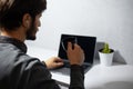 Close-up portrait of young man drinking coffee and working at laptop. Using wireless earphones. Stay home. Royalty Free Stock Photo