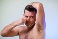 Close up portrait of man, smelling his armpit, feeling bad odor, wants to take a shower, needs antiperspirants