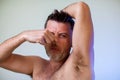 Close up portrait of man, smelling his armpit, feeling bad odor, wants to take a shower, needs antiperspirants