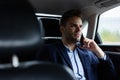 Close up portrait of young man in suit talking on the phone while sitting on the back seat of the car. Handsome young Royalty Free Stock Photo