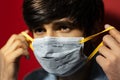 Close-up portrait of young man, takes off the medical flu mask, on background of red color. Royalty Free Stock Photo