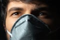 Close-up portrait of young man wearing respiratory face mask on black background. Royalty Free Stock Photo