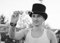 Close-up portrait of young man, wearing white top and black classic hat, holding sunglasses, smiling. Black and white picture of Royalty Free Stock Photo