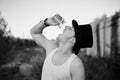 Close-up portrait of young man, wearing,white top, black classic hat, holding water glass, drinking last drops. Black and white Royalty Free Stock Photo