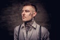 Close-up portrait of a young old-fashioned tattooed guy wearing white shirt and suspenders. on dark background. Royalty Free Stock Photo