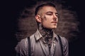 Close-up portrait of a young old-fashioned tattooed guy wearing white shirt and suspenders. Isolated on dark background. Royalty Free Stock Photo