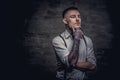 Close-up portrait of a young old-fashioned tattooed guy wearing white shirt and suspenders. Isolated on dark background. Royalty Free Stock Photo