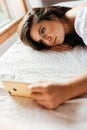 Close up portrait of young sad woman lying on the bed looking at her smartphone feels unhappy. Waiting for mobile message. Feeling Royalty Free Stock Photo