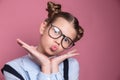 Close-up portrait of a young school girl with glasses having fun on pink background Royalty Free Stock Photo