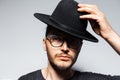 Close-up portrait of young serious handsome man wearing black hat and glasses. Royalty Free Stock Photo