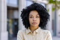 Close-up portrait of young serious thinking woman outside office building, business woman with curly hair looking at Royalty Free Stock Photo