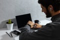 Close-up portrait of young smiling businessman verifies time on his smartwatch, using wireless earphones. Sitting in office. Royalty Free Stock Photo