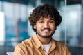Close-up portrait of a young smiling Indian man sitting and working in the office, looking confidently at the camera Royalty Free Stock Photo