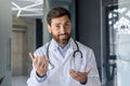 Close-up portrait of a young smiling male doctor who is in the hospital and talking via video link, conducting an online Royalty Free Stock Photo