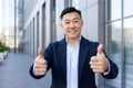 Close-up portrait of a young smiling and successful Asian male businessman standing on the street near an office center Royalty Free Stock Photo