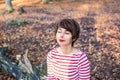 Close up portrait of young smiling woman with closed eyes sitting and relaxing on the fallen tree in autumnal forest. Autumn Royalty Free Stock Photo