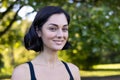 Close-up portrait of a young smiling woman in sporty black clothes standing outside in a park while exercising and Royalty Free Stock Photo