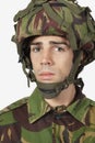 Close-up portrait of young soldier against gray background