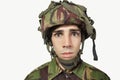 Close-up portrait of young soldier staring against gray background