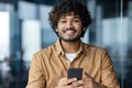 Close-up portrait of young successful Latin American businessman, man inside office at workplace smiling and looking at Royalty Free Stock Photo