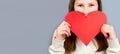 Close-up portrait of young teen girl holding in hands big large paper heart  on gray background. Cute little girl with a Royalty Free Stock Photo