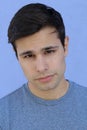 Close up portrait of a young teenager man looking at camera with an insecure expression, against a green background. Teenagers