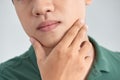 A close up portrait of young thinking man touching his chin with hand and standing against light grey background. Thinking out Royalty Free Stock Photo