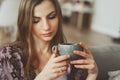 Close up portrait of young thoughtful woman with cup of tea or coffee sitting alone at home Royalty Free Stock Photo