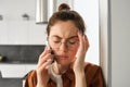 Close up portrait of young troubled, worried woman listens to voice message, having difficult phone conversation, answer