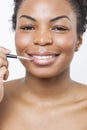 Close-up portrait of young woman applying lip gloss with brush Royalty Free Stock Photo
