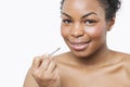 Close-up portrait of young woman applying lip gloss with brush Royalty Free Stock Photo