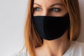 Close-up portrait of a young woman in a black medical mask and white T-shirt on white background. Royalty Free Stock Photo