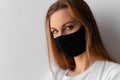 Close-up portrait of a young woman in a black medical mask and white T-shirt on white background. Royalty Free Stock Photo