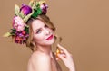 Close-up portrait of young woman in floral wreath spraying perfume isolated on ocher background Royalty Free Stock Photo