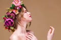 Close-up portrait of young woman in floral wreath spraying perfume isolated on ocher background Royalty Free Stock Photo