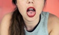 Close up portrait of young woman with freckles sticking out pierced tongue, showing her tongue piercing with pink background Royalty Free Stock Photo