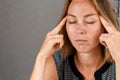 A close-up portrait of a young woman with her eyes closed and her hands on her temples. Concept of health, stress and psychology