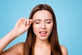 Close up portrait of young woman plucking eyebrows with tweezers, having pain, standing over grey background Royalty Free Stock Photo