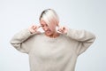 Close up portrait of young woman plugging ears with fingers.