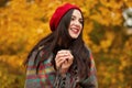 Close up portrait of young woman wearing red beretand wrapped checkered blanket, having picnic in forest, drinking tea from Royalty Free Stock Photo