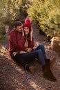 Close-up portraits of young couple in red checkered shirts sitting among Christmas tree seedlings
