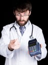 Close-up portret of a Doctor holding pos-terminal, stethoscope around his neck. He rubs his thumb and forefinger Royalty Free Stock Photo