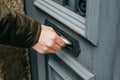 Close-up. The postman puts a letter or newspaper or magazine in the mailbox at the door of a residential building or a