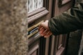 Close-up. The postman puts a letter or newspaper or magazine in the mailbox at the door of a residential building or a