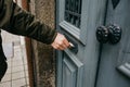 Close-up. The postman puts a letter or newspaper or magazine in the mailbox at the door of a residential building or a