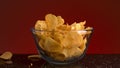 Close up of potato chips falling inside the transparent glass bowl and on the table. Stock footage. Crispy junk product Royalty Free Stock Photo