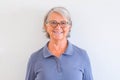 Close up and potrait of mature woman smiling and looking at the camera with a white wall at the background - active senior concept Royalty Free Stock Photo